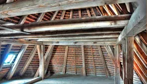 Innenansicht eines Dachstuhls mit sichtbaren Holzbalken und Dachsparren.