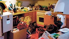 Kleine mit Müll und Kartons zugestellte Küche einer Messiewohnung.